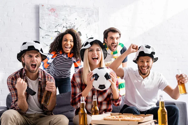 Fröhliche multikulturelle Fußballfans brüllen, während sie die Meisterschaft zu Hause verfolgen — Stockfoto