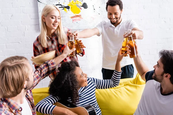 Cheerful african american man giving bottles of beer to multiethnic friends during party — Stock Photo