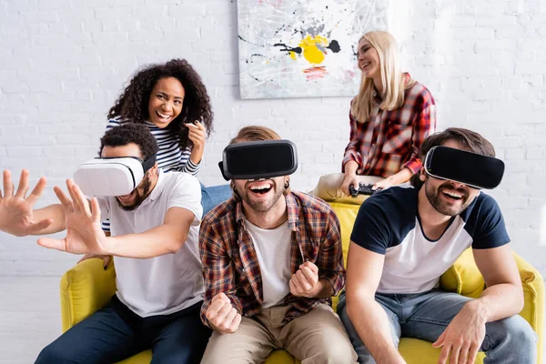 QUIIV, UCRÂNIA - OUTUBRO 19, 2020: mulher afro-americana rindo apontando com o dedo perto de amigos multiculturais excitados usando fones de ouvido vr — Fotografia de Stock