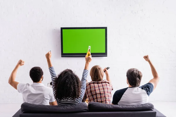 Visão traseira de fãs de esportes multiculturais mostrando gesto de sucesso enquanto assiste campeonato na tv — Fotografia de Stock