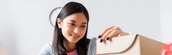 Happy asian volunteer looking at carton box, banner — Stock Photo