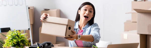 Excited asian volunteer with open mouth showing carton box in charity center, banner — Stock Photo