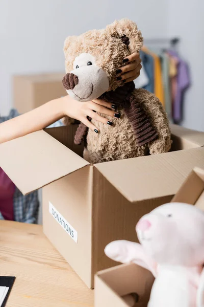 Ausgeschnittene Ansicht von Freiwilligen, die Stofftiere in der Nähe von Schachteln mit Spendenaufdruck in Charity-Büro halten — Stockfoto