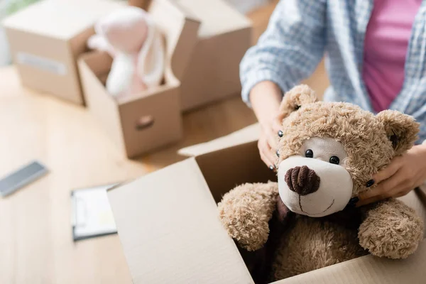 Vue recadrée du bénévole mettant un jouet mou dans un emballage en carton dans un centre de bienfaisance — Photo de stock