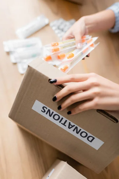 Cropped view of woman holding syringes near box with donations lettering in charity center — Stock Photo