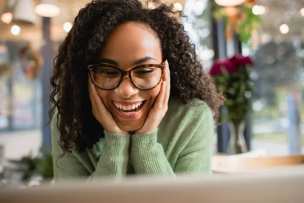 Femme afro-américaine étonnée dans des lunettes touchant les joues — Photo de stock