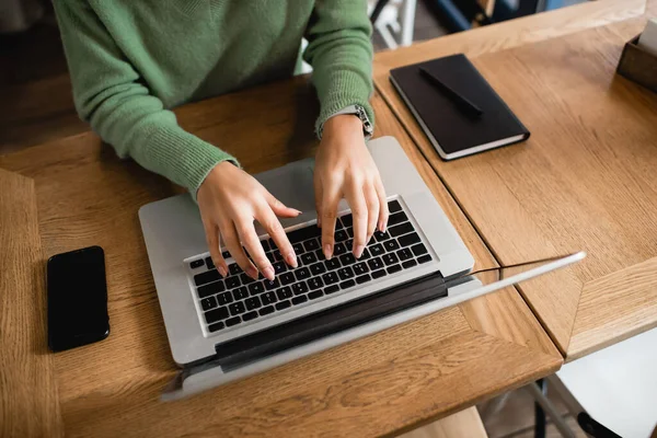 Vue recadrée de femme afro-américaine tapant sur le clavier de l'ordinateur portable dans le café — Photo de stock