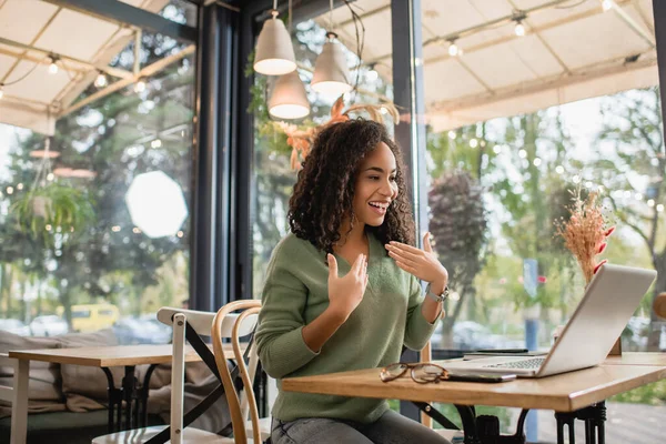 Flattered african american woman looking at laptop on table in cafe — Stock Photo