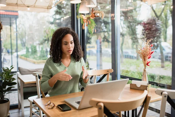 Ricci afroamericani donna gesticolare mentre spiega e guardando il computer portatile durante la videochiamata — Foto stock