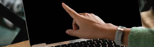 Vista parcial de la mujer afroamericana señalando con el dedo a la computadora portátil con pantalla en blanco, bandera - foto de stock