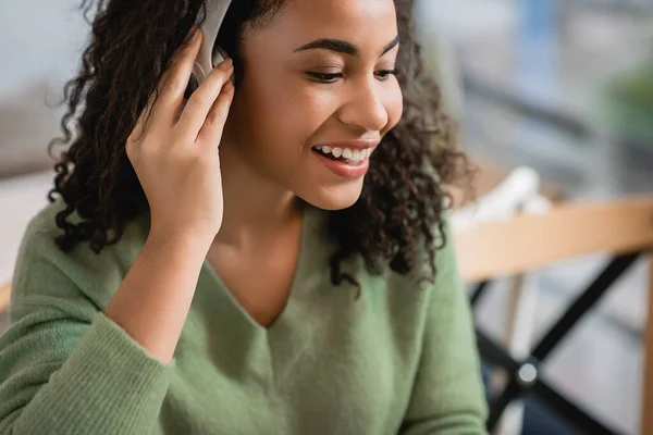 Feliz afro-americana mulher ouvindo podcast no café — Fotografia de Stock