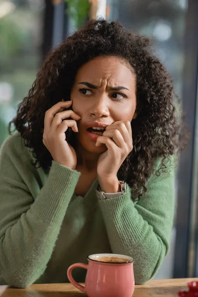 Afraid african american woman talking on smartphone in cafe — Stock Photo