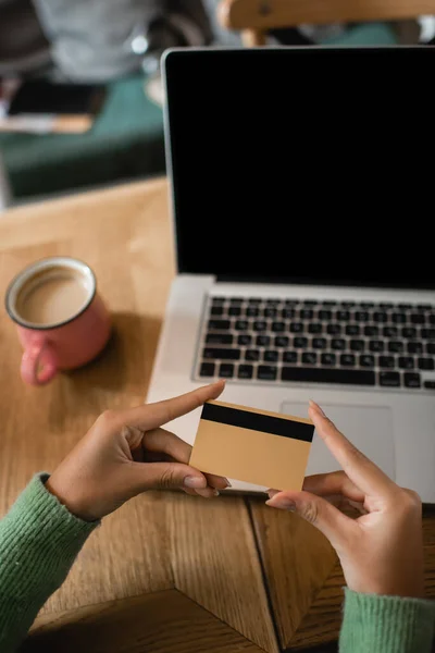 Cropped view of african american woman holding credit card near laptop with blank screen — Stock Photo