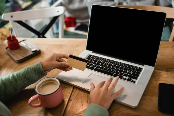 Vista recortada de mujer afroamericana sosteniendo tarjeta de crédito cerca de gadgets con pantalla en blanco - foto de stock