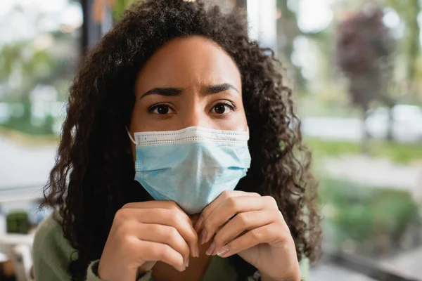 Mujer afroamericana en máscara médica mirando la cámara - foto de stock