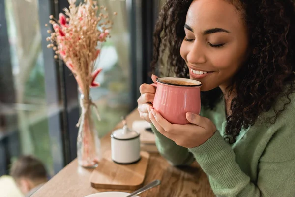 Mulher americana africana satisfeito segurando xícara rosa com café no café — Fotografia de Stock