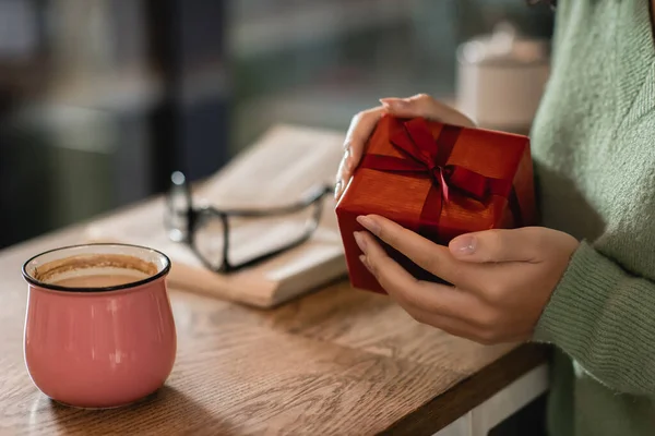 Vue recadrée de femme afro-américaine tenant enveloppé Noël présent dans le café — Photo de stock