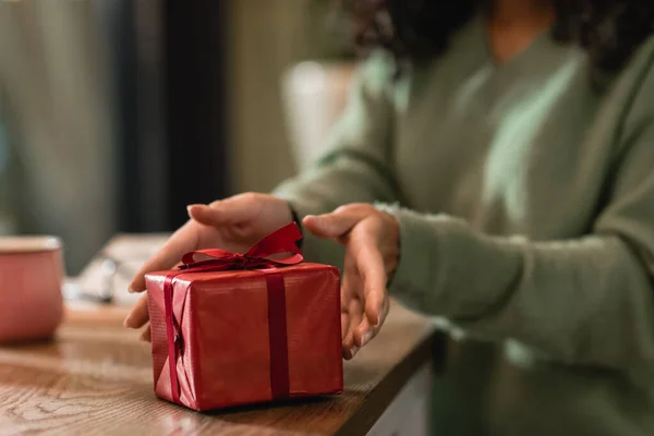 Wrapped christmas present near african american woman in cafe — Stock Photo