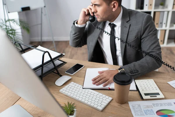 Hombre de negocios serio hablando por teléfono en el lugar de trabajo en la oficina - foto de stock