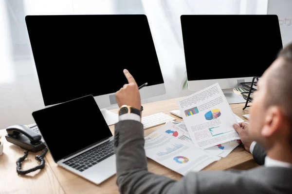 Cropped view of trader pointing with finger at monitor with blank screen, blurred foreground — Stock Photo