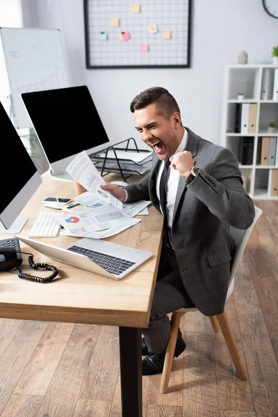 Comerciante animado gritando e mostrando gesto vencedor no local de trabalho — Fotografia de Stock