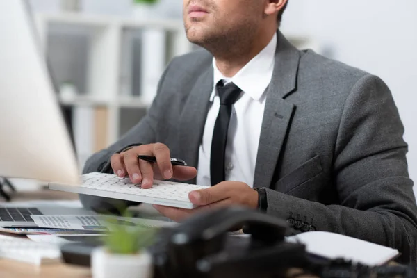Cropped view of trader typing on keyboard in office, blurred foreground — Stock Photo