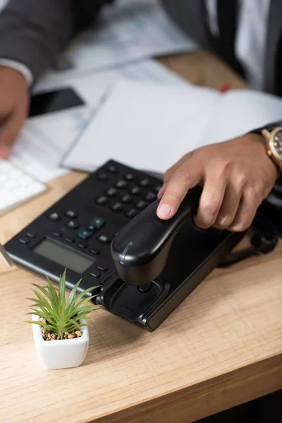 Vista cortada de empresário tomando aparelho de telefone fixo, fundo embaçado — Fotografia de Stock