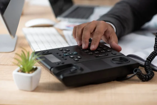 Partial view of businessman dialing on landline phone, blurred foreground — Stock Photo
