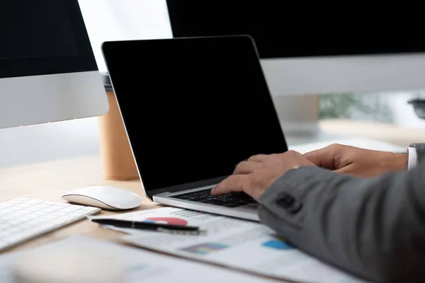 Vue partielle de l'homme d'affaires tapant sur ordinateur portable sur le lieu de travail, premier plan flou — Photo de stock