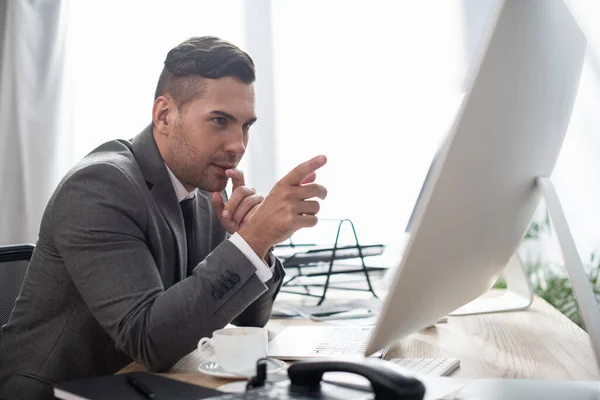 Concentrated trader pointing with finger at monitor, blurred foreground — Stock Photo
