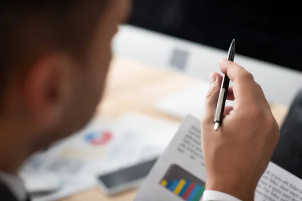 Vista ritagliata del commerciante che punta con penna in primo piano sfocato — Foto stock