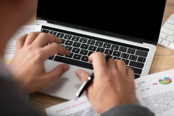 Partial view of trader typing on laptop at workplace, blurred foreground — Stock Photo
