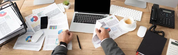 Ausgeschnittene Ansicht des Händlers in der Nähe von Laptop und Papieren mit Diagrammen und Diagrammen, Banner — Stockfoto