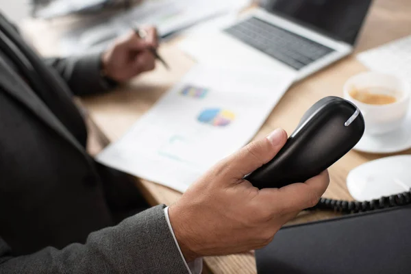 Partial view of trader holding handset of telephone, blurred background — Stock Photo