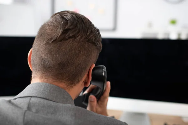 Vista posteriore del commerciante che parla al telefono vicino ai monitor del computer — Foto stock