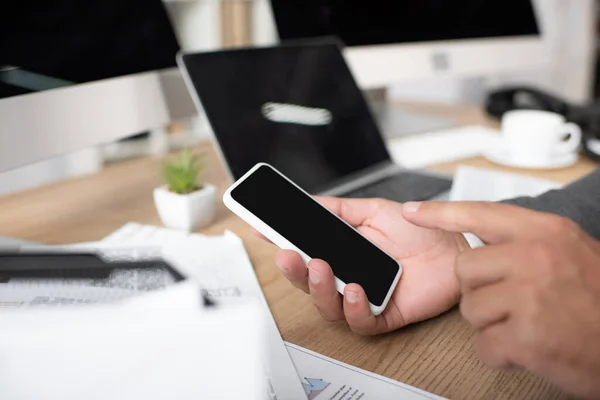 Vista recortada del hombre de negocios que apunta con el dedo al teléfono inteligente con pantalla en blanco, enfoque selectivo - foto de stock