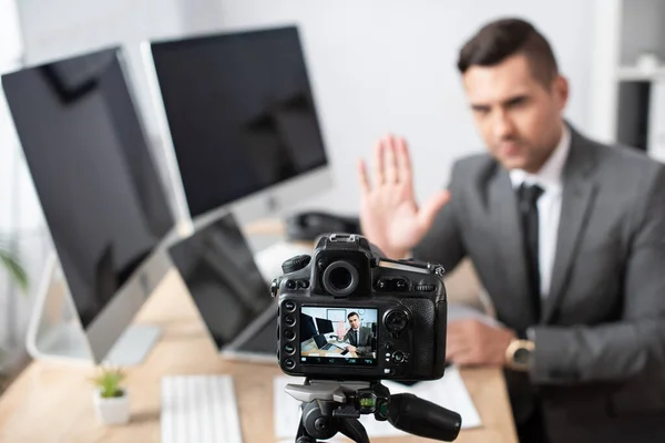 Enfoque selectivo de la cámara digital cerca del comerciante agitando la mano sobre fondo borroso - foto de stock