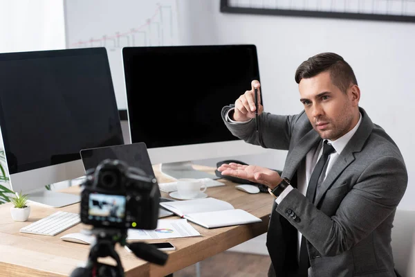 Comerciante demostrando recesión con pluma durante la transmisión en línea en la cámara digital, borrosa primer plano - foto de stock