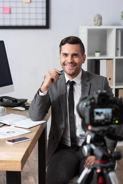 Uomo d'affari sorridente che registra video sulla fotocamera digitale, primo piano sfocato — Foto stock