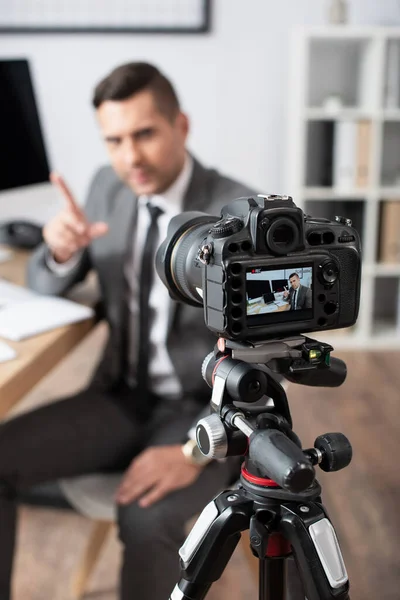 Selektiver Fokus der Digitalkamera in der Nähe des Händlers, der beim Online-Streaming mit dem Finger auf verschwommenen Hintergrund zeigt — Stockfoto