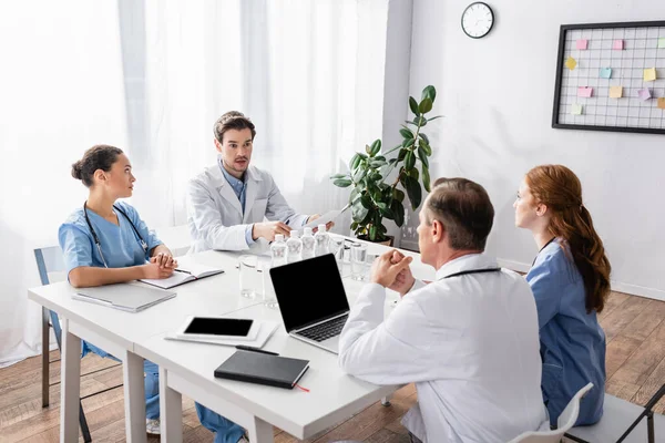 Multicultural doctors and nurses working with papers and devices in clinic — Stock Photo
