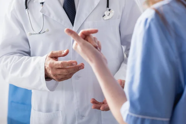 Cropped view of doctor standing near nurse on blurred foreground — Stock Photo