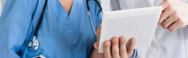 Cropped view of doctor and nurse using digital tablet in clinic, banner — Stock Photo