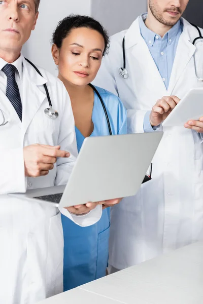 African american nurse standing near doctors with devices in clinic — Stock Photo