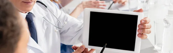 Обрезанный вид врача, держащего цифровой планшет с пустым экраном рядом с коллегой на размытом переднем плане, баннер — стоковое фото