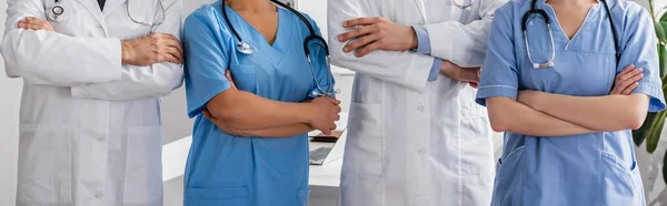 Vista ritagliata di infermieri multiculturali e medici con le braccia incrociate in piedi insieme in ospedale, striscione — Foto stock
