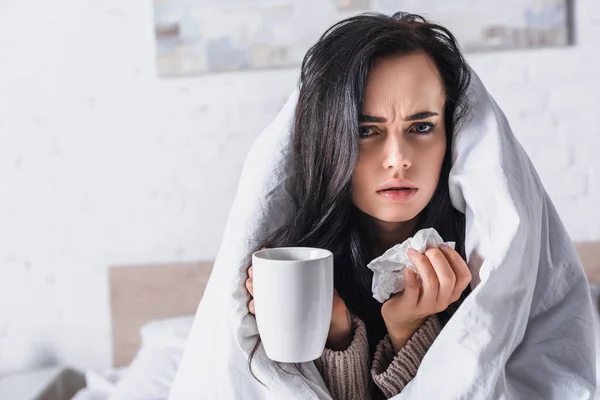 Malade jeune femme brune avec tissu et boisson chaude au lit — Photo de stock