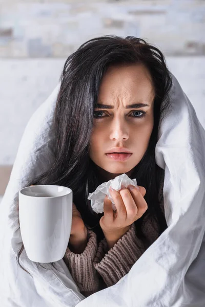 Malade jeune femme brune avec tissu et boisson chaude au lit — Photo de stock