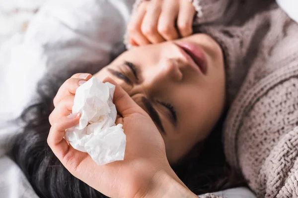 Sick young brunette woman with tissue in bed — Stock Photo