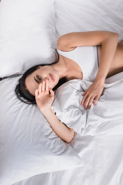 Giovane donna bruna in biancheria intima sdraiata a letto — Foto stock